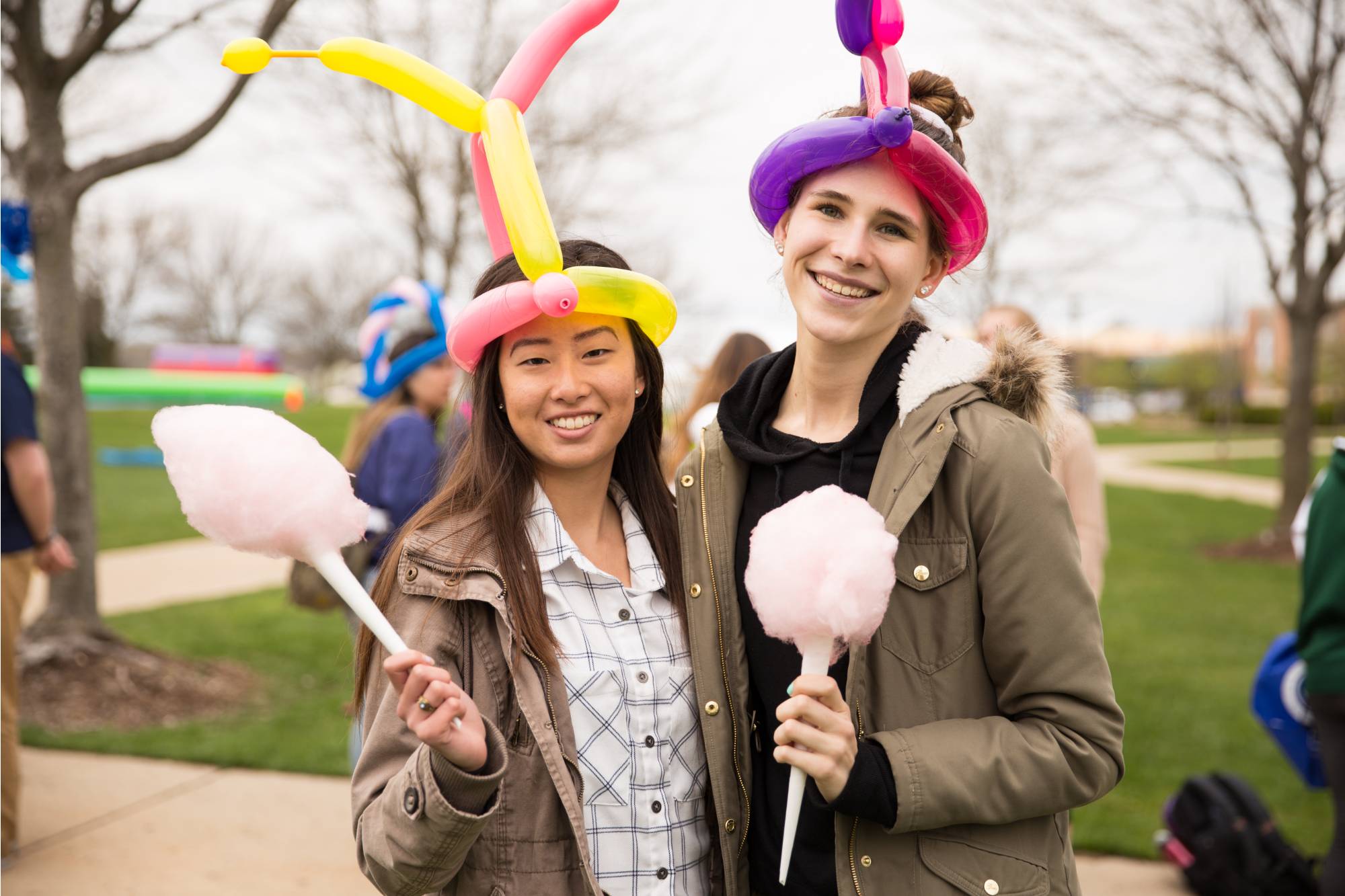 2 GVSU students holding cotton candy with balloon hats at ExtravaGRANDza